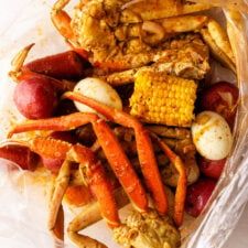 crab legs, corn on the cob and potatoes in a plastic bag