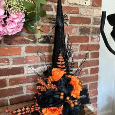 a black and orange halloween decoration on a shelf next to a brick wall with flowers