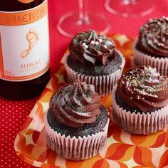 cupcakes with chocolate frosting and sprinkles next to a bottle of wine