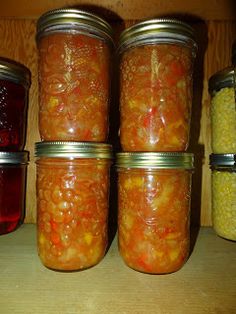 several jars filled with food sitting on top of a wooden shelf next to each other