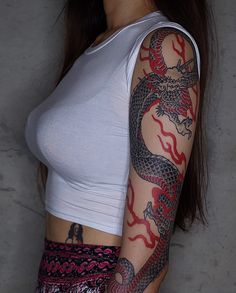 a woman with a dragon tattoo on her arm and shoulder is posing for the camera