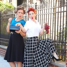 two women standing next to each other near a fence