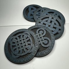 four black coasters sitting on top of a white table