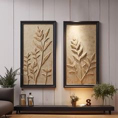 there are two framed pictures on the wall next to a table with a plant in it