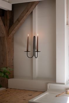 two candles are hanging on the wall next to a bathtub in a room with exposed beams