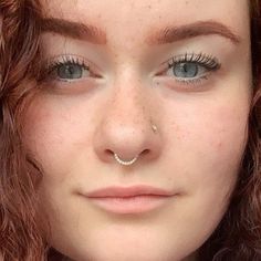 a close up of a person wearing a nose ring and piercing on it's nose