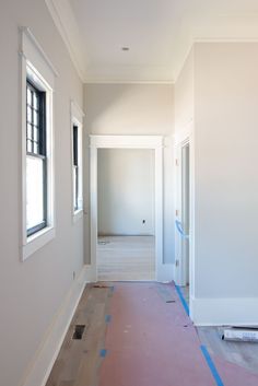 an empty room is being painted white with blue tape on the floor and window frames