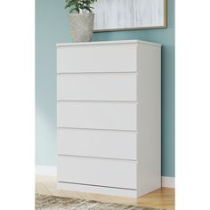 a white chest of drawers sitting on top of a wooden floor next to a blue wall