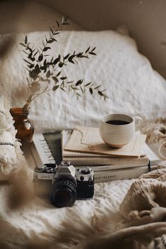 a camera, book and cup on a bed