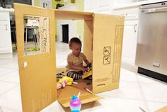 a young child sitting inside of a cardboard box