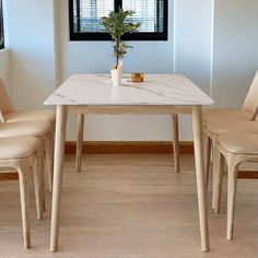 a dining table with four chairs and a vase on the table in front of it