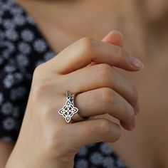 a close up of a person wearing a ring with a flower design on the middle