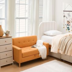 a bed room with a neatly made bed next to a chair and a desk in front of a window