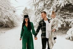 a man and woman walking in the snow with a baby on their back holding hands