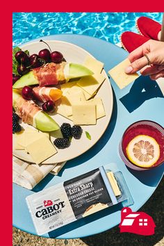 a plate of fruit and cheese next to a pool