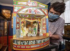 a man wearing a face mask and covering his mouth in front of a carnival machine