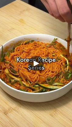 a person chopping up noodles in a bowl on a wooden table with the words korea recipe series written above it