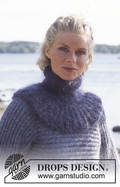 a woman standing on the beach wearing a sweater