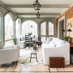 a living room filled with white furniture and lots of windows next to a fire place