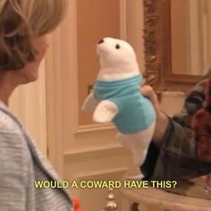 a person holding a stuffed animal in front of a mirror with the caption would a coward have this?