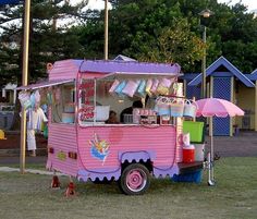 a pink food truck parked on top of a grass covered field