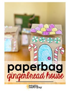 a paper bag gingerbread house sitting on top of a wooden table with candy canes