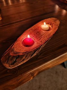 two lit candles sit on a wooden tray