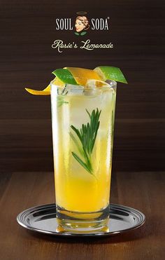 a tall glass filled with lemonade and garnished with green leaves on the rim