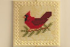 a red bird is sitting on top of a needle - embroidered wall hanging ornament