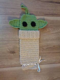 a crocheted baby yoda hat on top of a wooden floor