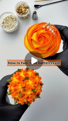 two hands are holding an orange flower on top of a white table with bowls and utensils