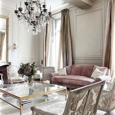 a living room filled with furniture and a chandelier above a glass coffee table