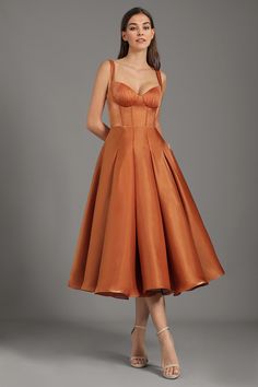 a woman in an orange dress poses for the camera