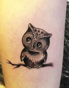 an owl tattoo on the arm with a hat on it's head and eyes