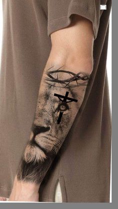 a man with a tattoo on his arm has a lion and cross tattooed on it