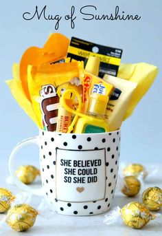 a mug filled with candy and candies on top of a white table next to yellow flowers