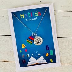 a card with an open book and a necklace that says matilda the musical on it