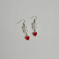 red heart and white pearl earrings with silver earwires on a white table top