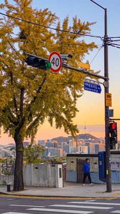 a street sign on a pole next to a tree with yellow leaves and buildings in the background