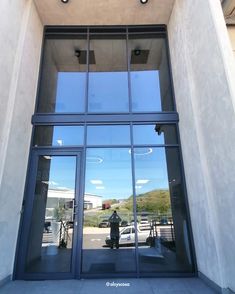 the reflection of a man standing in front of a building's glass door and windows