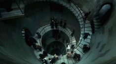 several people are standing in the middle of a spiral stair case, looking down at them