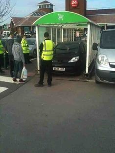 a man standing next to a parked car in front of a small building with a green awning