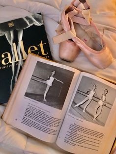 an open book and ballet shoes on a bed