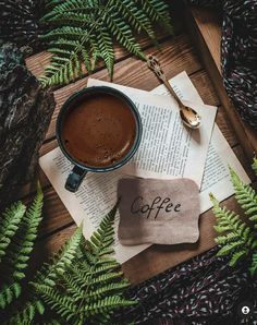 a cup of coffee sitting on top of an open book with the word coffee next to it