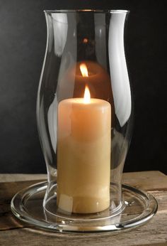 a lit candle in a glass vase on a wooden table