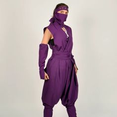 a woman wearing a purple outfit with a mask on her face and one hand in the other's pocket