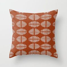 an orange and white pillow on a white wall with the pattern in shades of brown