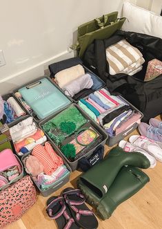 an open suitcase sitting on top of a wooden floor next to shoes and other items