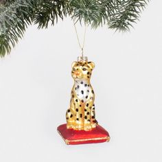 a christmas ornament shaped like a cheetah sitting on a red cushion