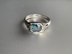 a close up of a ring with a stone in it on a gray surface,